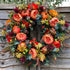 Autumn wreath with artificial flowers, pumpkins and foliage